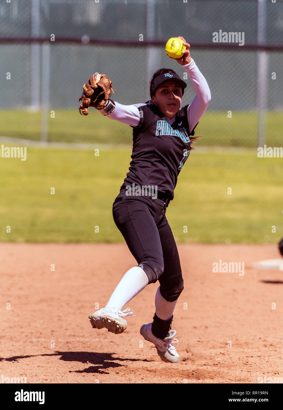 Le softball player en uniforme noir en milieu de vent jusqu'au cours de la main gauche pendant le jeu de livraison entre la technologie Foothill High School et Pioneer Vall Banque D'Images