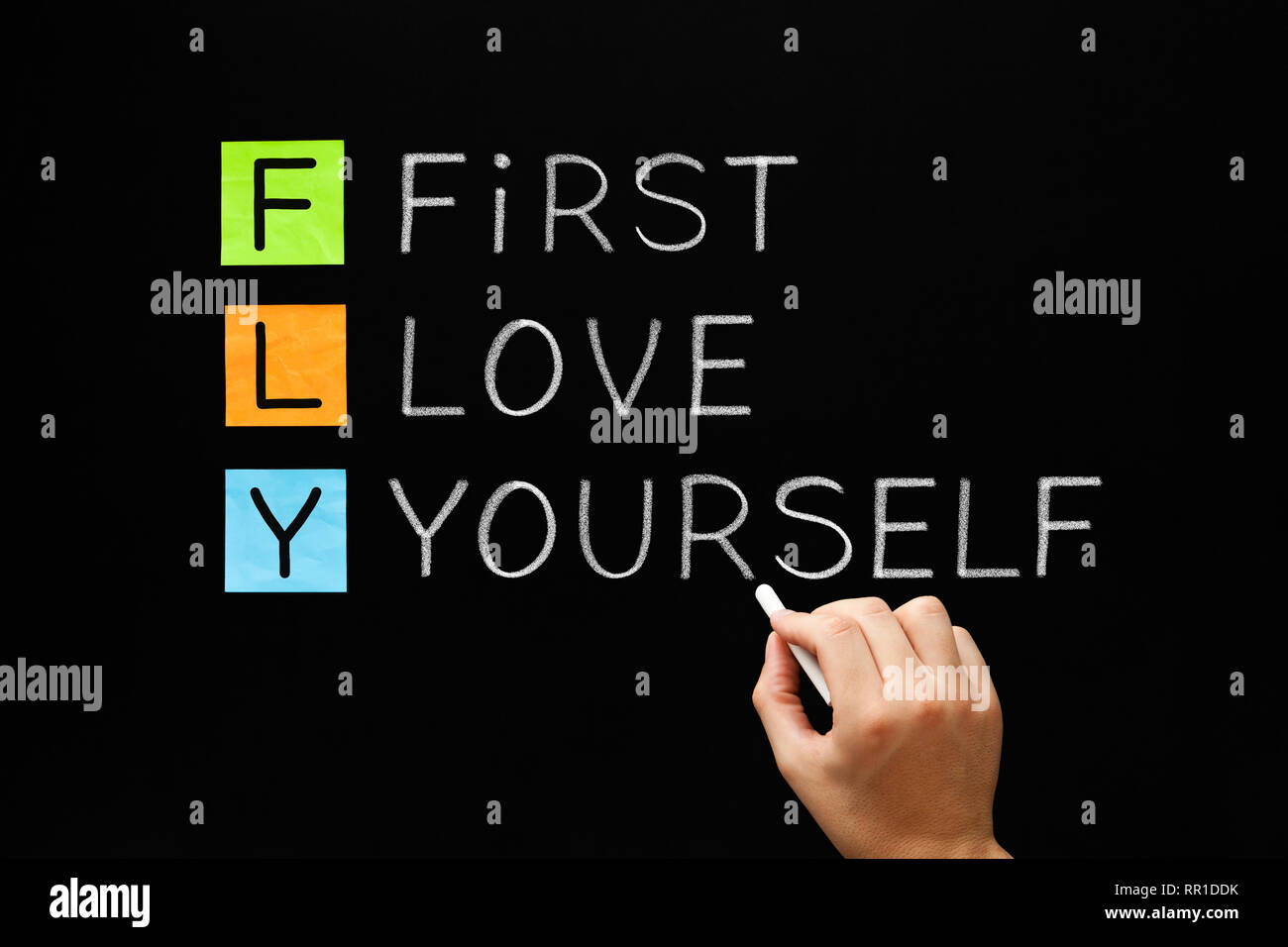 La main FLY - premier amour vous-même acronyme avec craie blanche sur tableau noir. L'amour de soi, l'acceptation et le bonheur concept. Banque D'Images