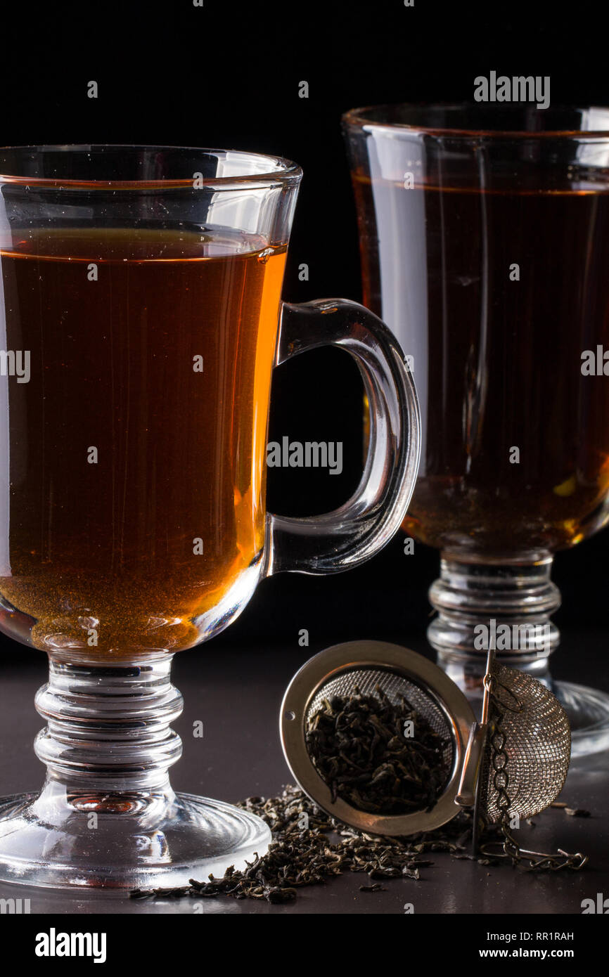 Un verre de thé avec un tamis sur un fond sombre Banque D'Images