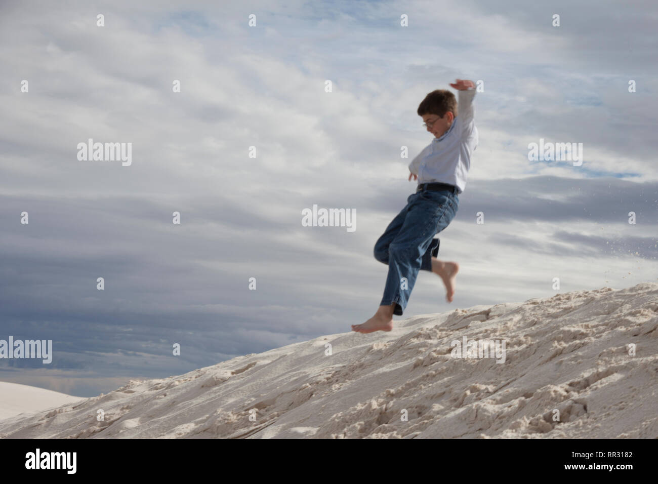 Petit gars sautant de dune de sable Banque D'Images