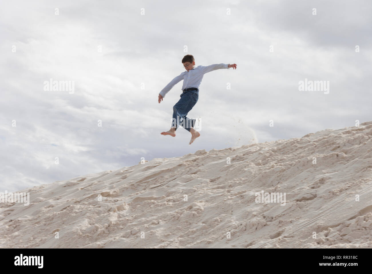 Garçon sautant sur une dune de sable Banque D'Images