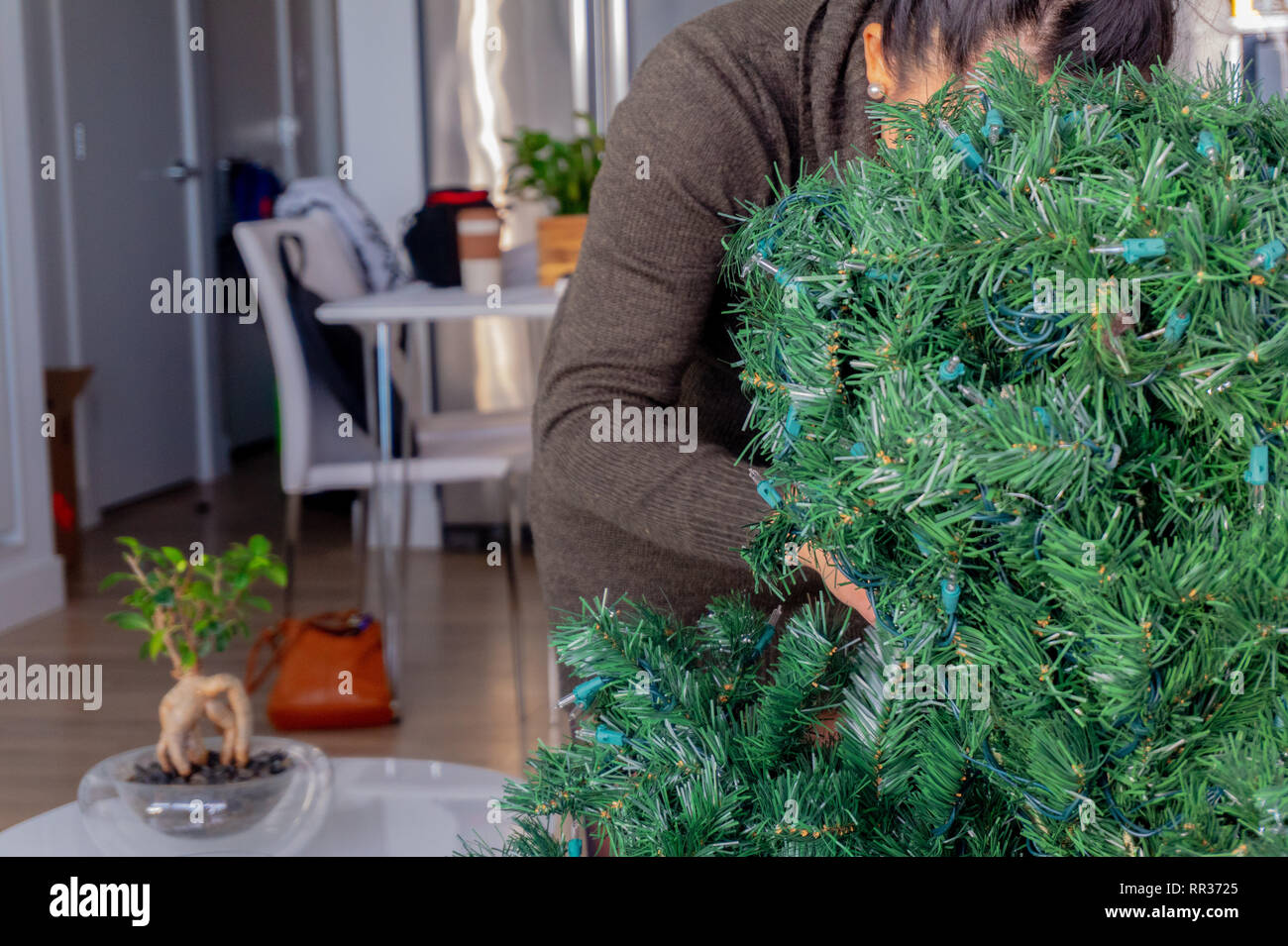 Femme derrière un arbre de Noël artificiel, mise en place de la maison de décoration par branches unraveling Banque D'Images