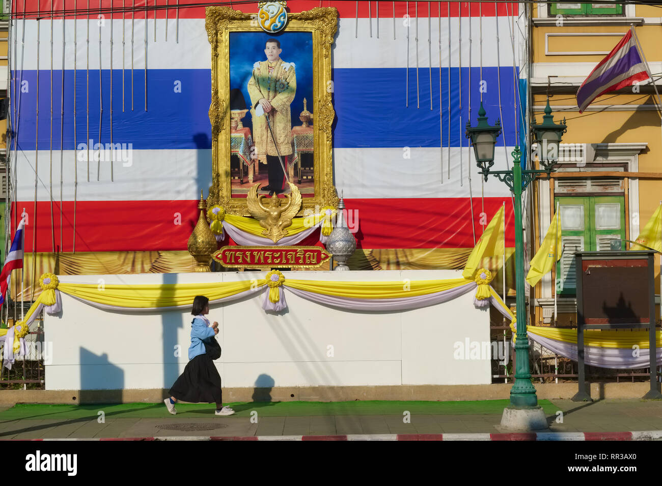 Une écolière à Bangkok, Thaïlande, passe sous un portrait du roi Maha Vajiralongkorn, Rama X., défini dans un pavillon thaï géant Banque D'Images