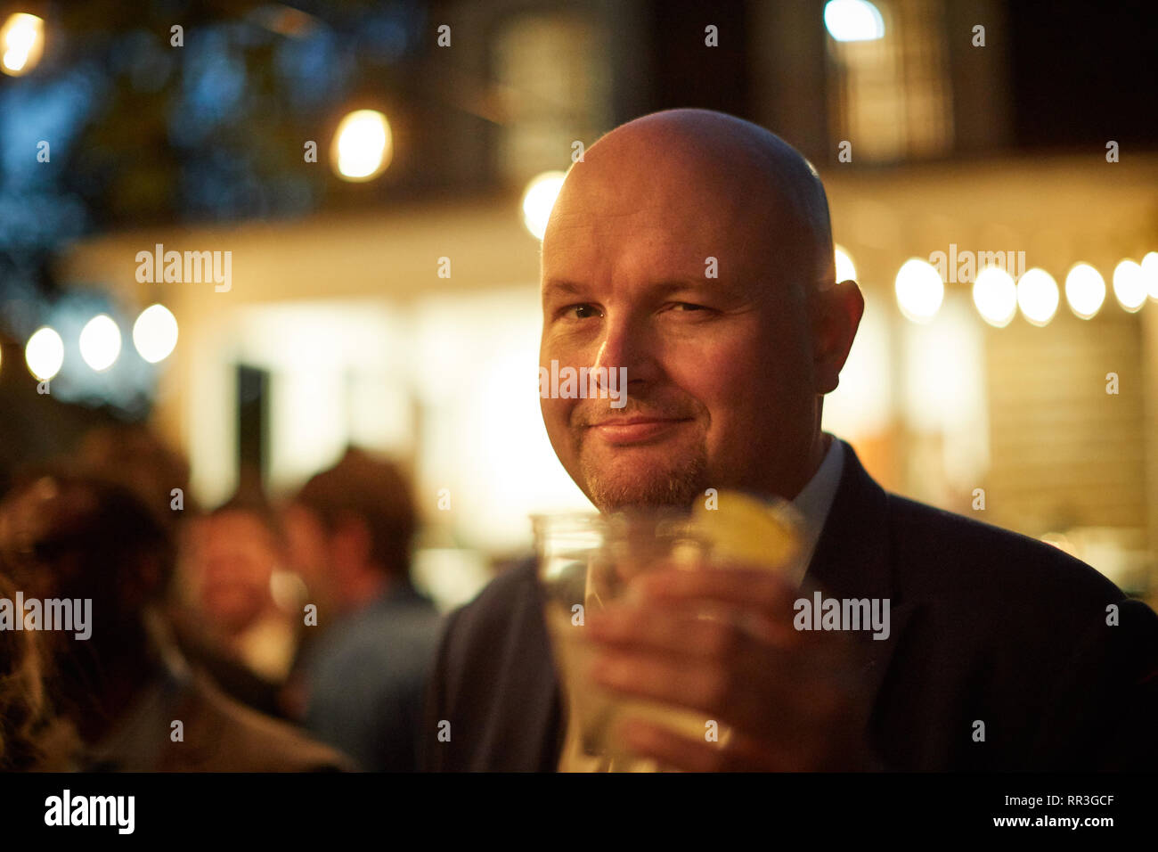 Confiant smiling man toasting avec boisson dans la main dans la nuit Banque D'Images