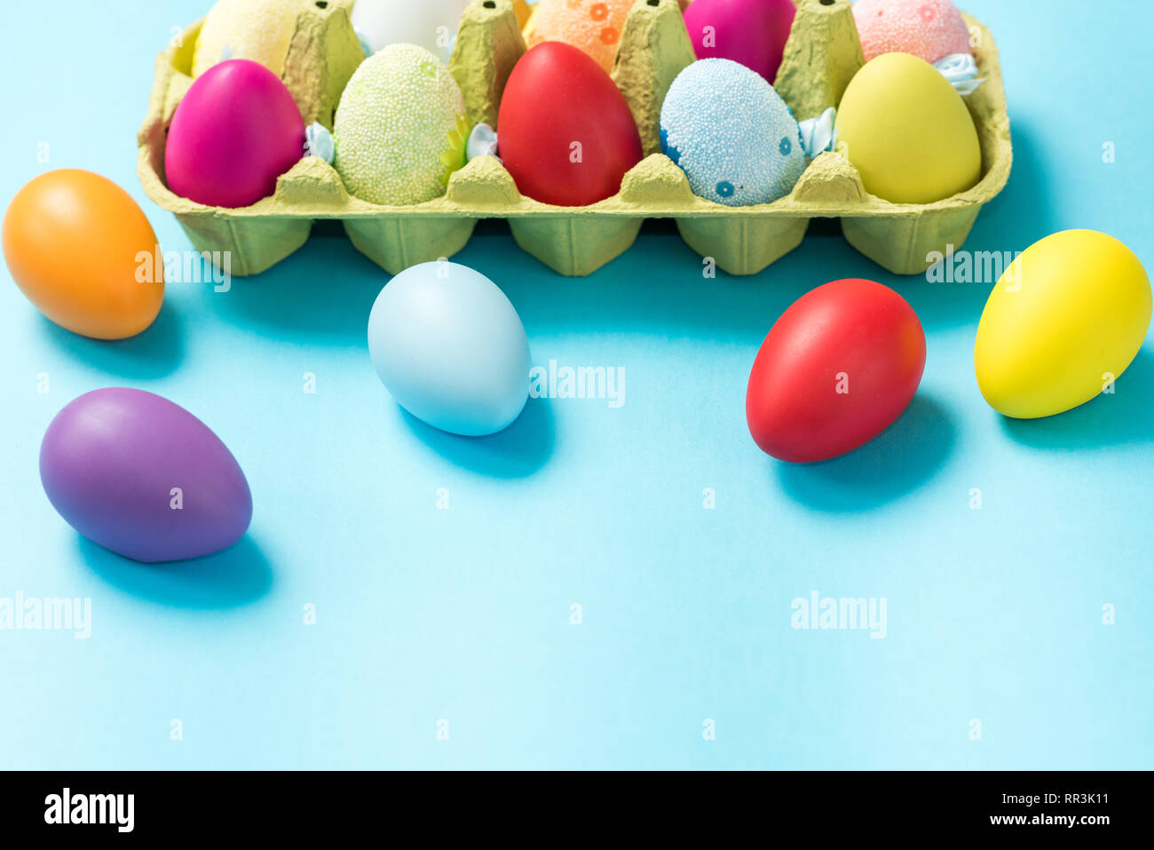Les oeufs de pâques sont décorées dans des couleurs vives, est abrité dans un éco-emballage en carton. Fond bleu. Idées de Pâques. L'espace pour le texte. Bac Eco oeuf Joyeuses Pâques. Banque D'Images