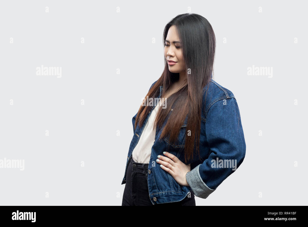 La douleur rénale ou spin. Vue côté profil portrait de belle brune asian young woman in casual veste en jean bleu et permanent de toucher son dos. Banque D'Images