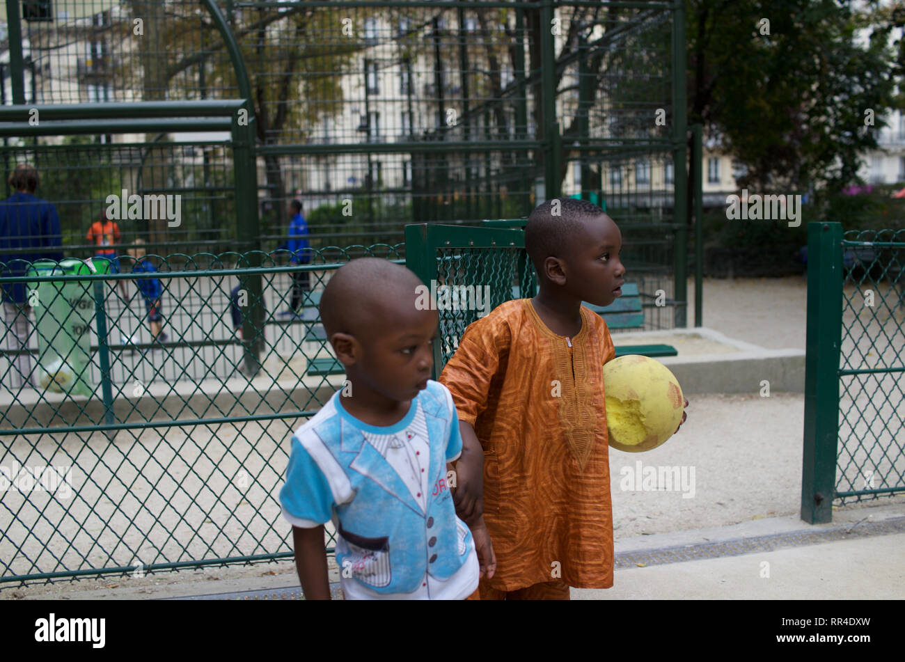 Les enfants français d'origine africaine, frères, de vêtements traditionnels chemise garçon dashiki, éponge holding ball, Square de Maubeuge, 75009, Paris, France Banque D'Images