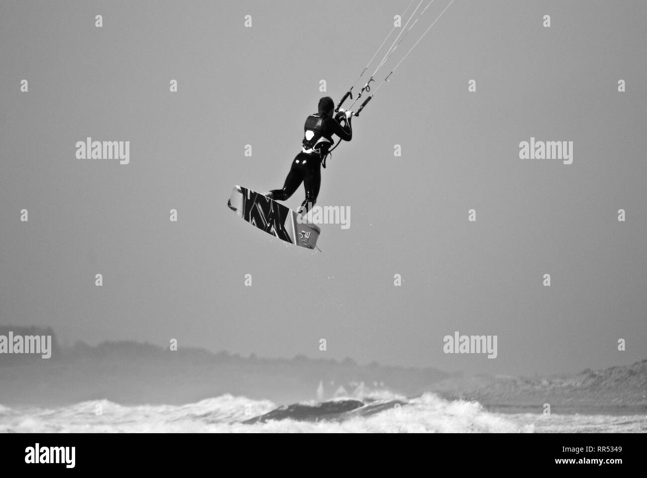 Un kite surfer est soulevé dans les airs en gris par temps couvert en conseil informatique, Anglesey, au nord du Pays de Galles, Royaume-Uni Banque D'Images