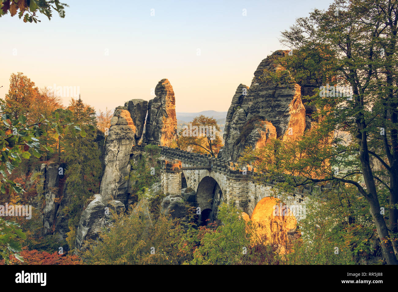 Bastei pont dans la Suisse saxonne parc national. Coucher du soleil dans des montagnes de grès de l'Elbe avec les arbres en couleurs d'automne et de formations rocheuses. Banque D'Images