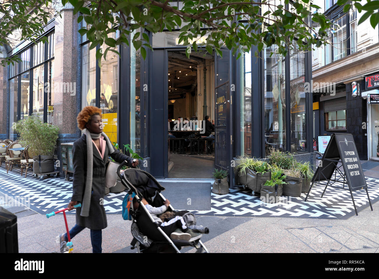 Femme enfant poussant à l'extérieur de l'hôtel Canova Italian restaurant café dans l'ancien grand magasin de style édouardien à Brixton, dans le sud de Londres SW9 UK KATHY DEWITT Banque D'Images