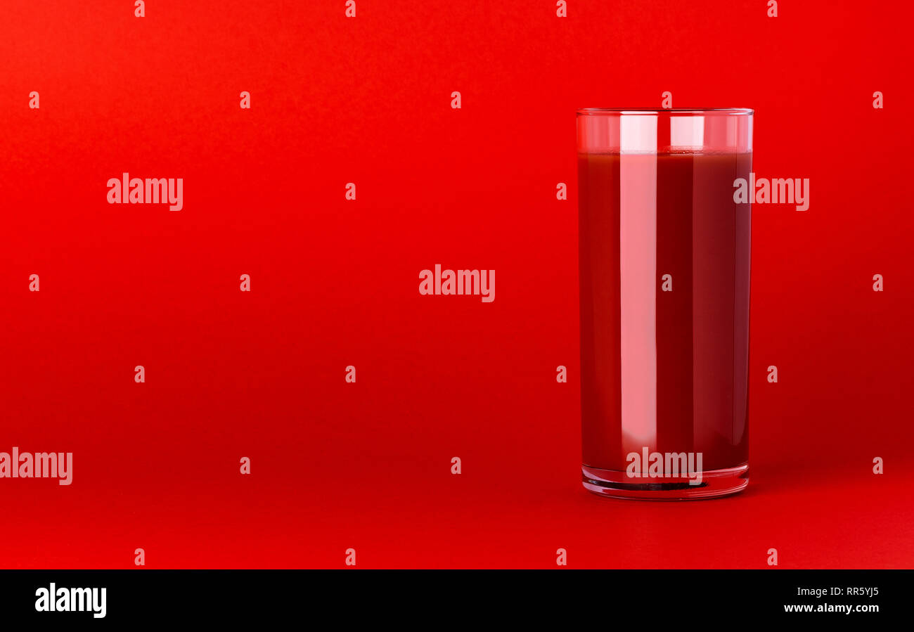 Un verre de jus de tomate sur fond rouge avec copie espace, cocktail bloody mary Banque D'Images