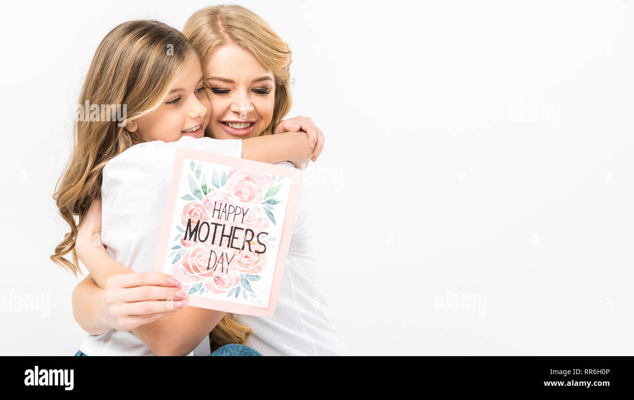 Adorable enfant hugging smiling mother avec plaisir la fête des mères, carte de souhaits dans la main sur fond blanc Banque D'Images