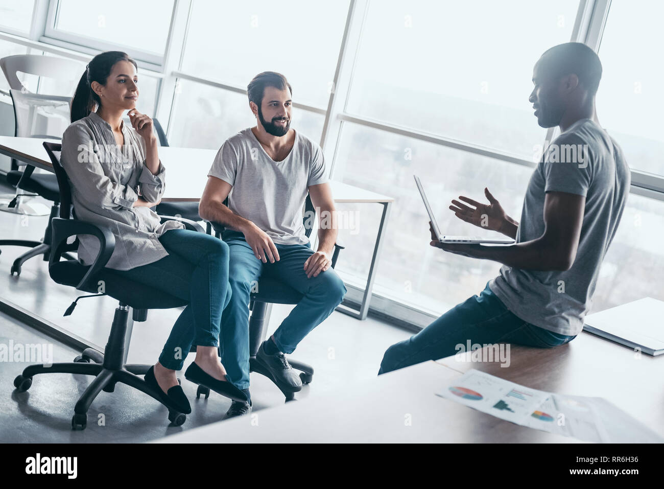 Groupe de rire multiraciale businesspeople talking et plaisantaient assis sur des chaises de bureau moderne et convivial, l'équipe entreprises multi-ethnique s'amuser, discuter de questions d'affaires à la réunion Banque D'Images