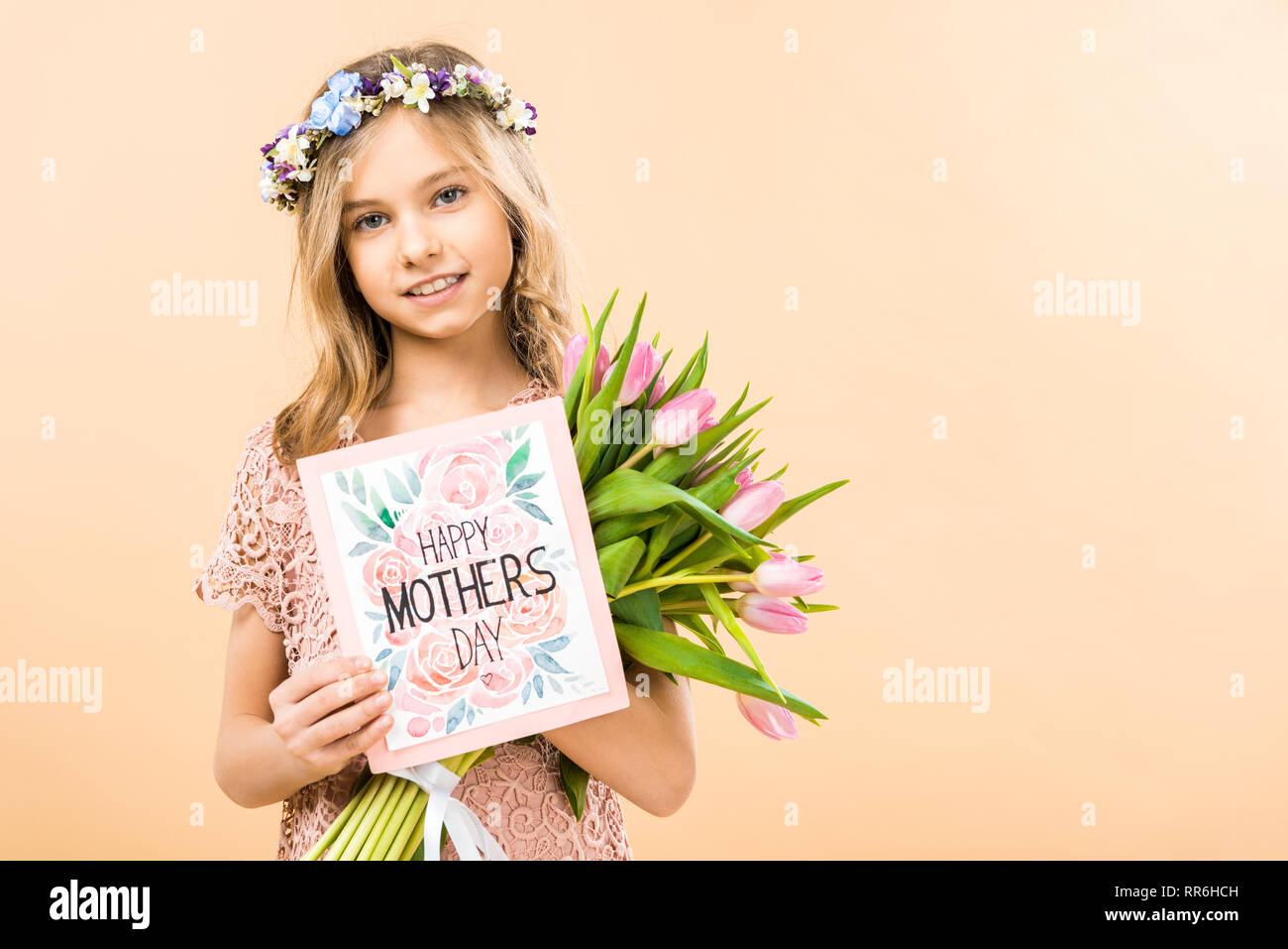 Adorable enfant avec bouquet de tulipes roses et heureuse fête des mères, carte de souhaits sur fond jaune Banque D'Images
