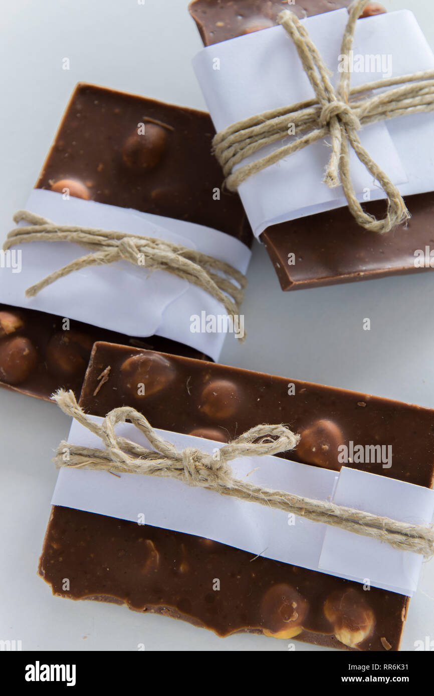 Vue de dessus de morceaux de chocolat enveloppé dans du papier blanc et ficelle rustique sur le fond blanc Banque D'Images