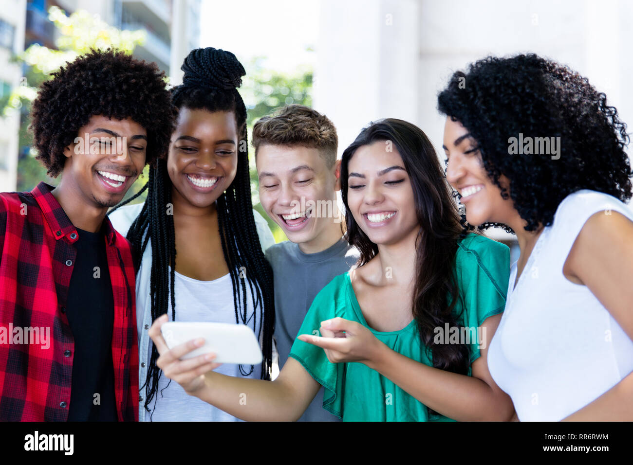 Groupe d'Amérique latine et d'Afrique de rire les jeunes adultes regardant outdoor clip dans la ville Banque D'Images
