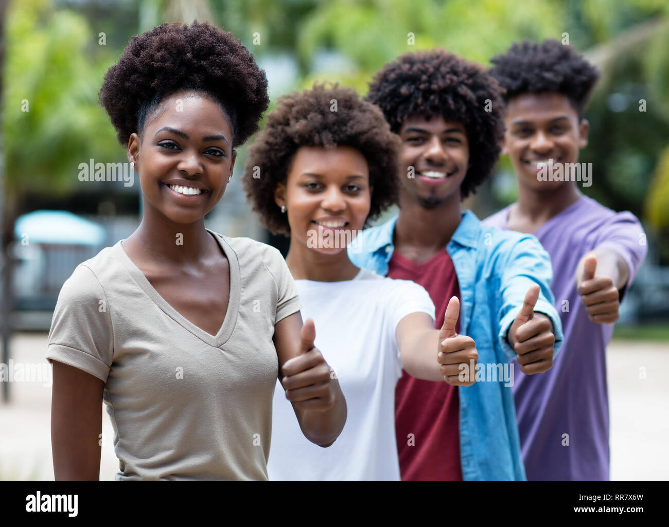 Groupe de jeunes adultes américains africains showing thumb up piscine en été Banque D'Images