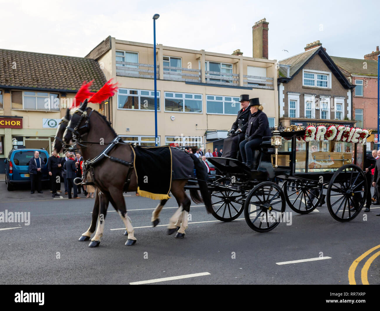 Des funérailles dans le Nord de l'Angleterre avec un corbillard tiré par deux chevaux noirs. Banque D'Images