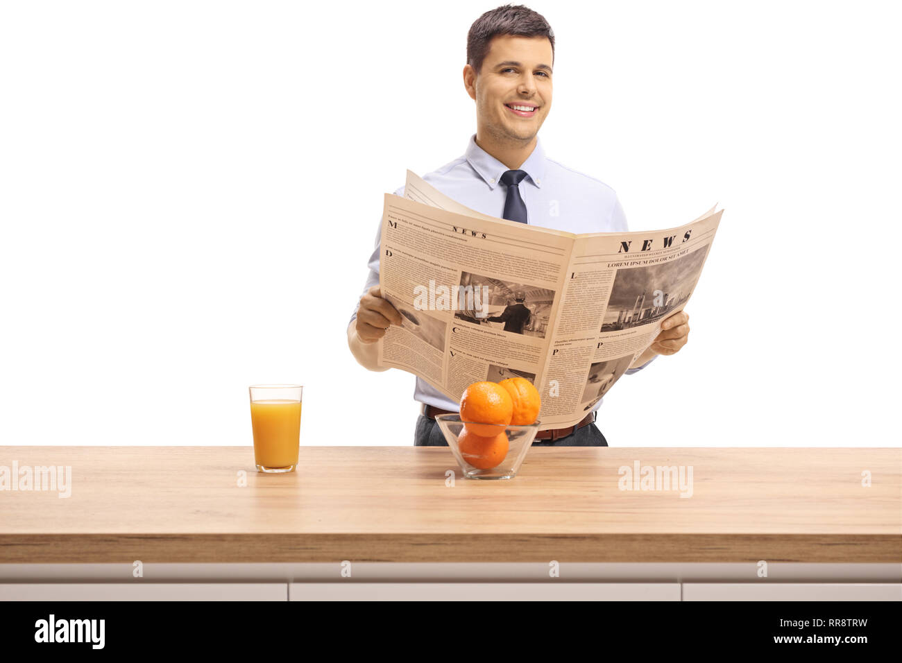 Jeune homme dans une chemise lire un journal derrière un des meubles en haut avec du jus d'orange et orange isolé sur fond blanc Banque D'Images