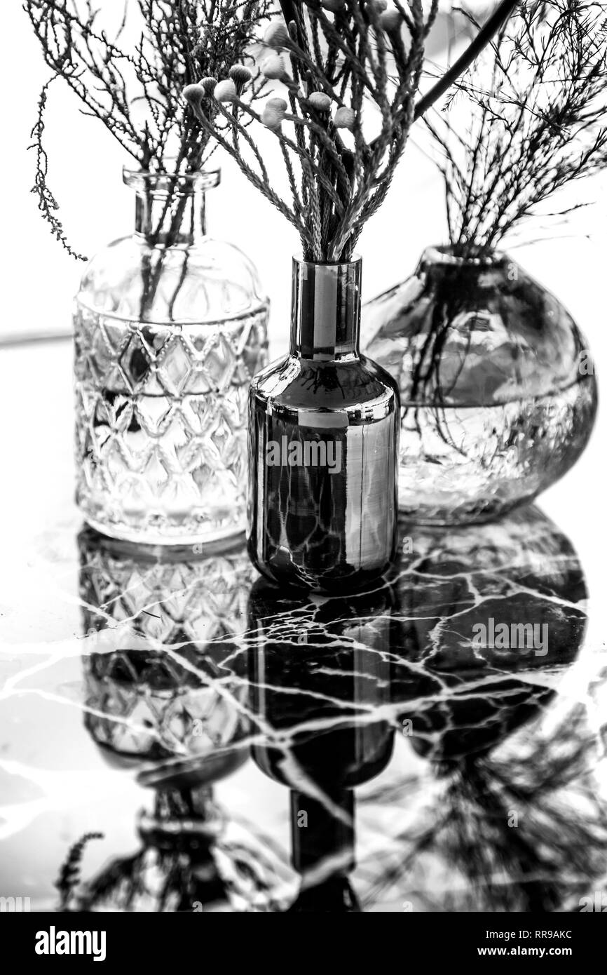 Vases en verre avec des fleurs sur table de marbre. Image en noir et blanc de vases de verre. Banque D'Images