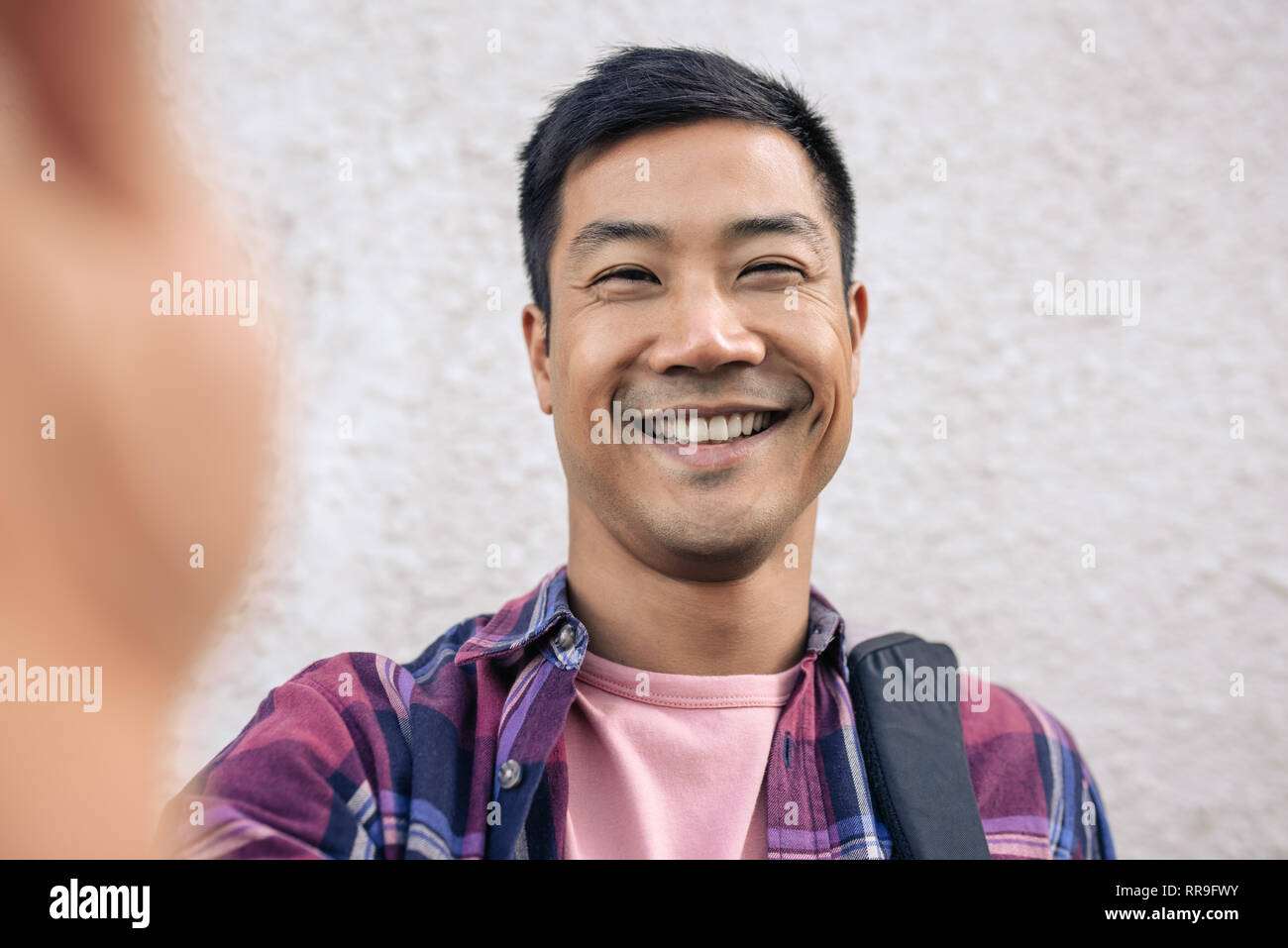 Smiling Young Asian man taking a dans la ville selfies Banque D'Images