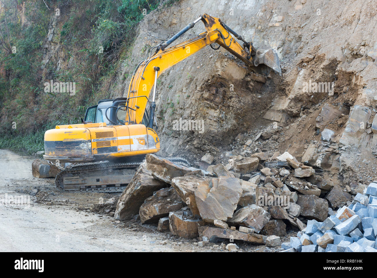 Une excavatrice creuse et perçoit le sol et la pierre pour un projet d'élargissement de la route Banque D'Images