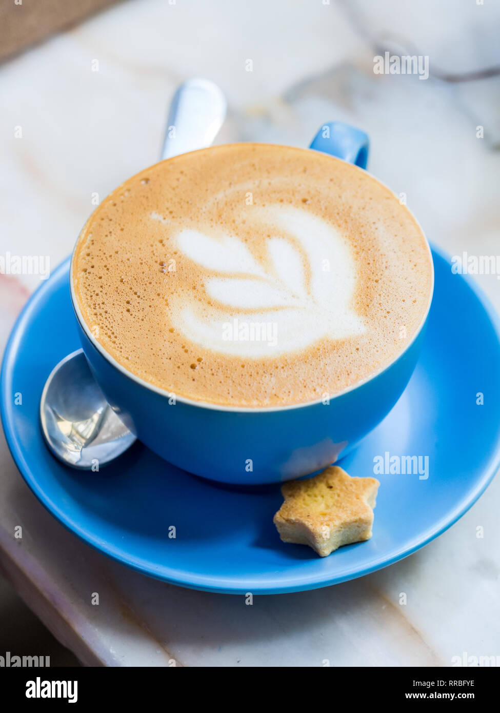 Cappuccino avec latte art dans une tasse bleue. Banque D'Images