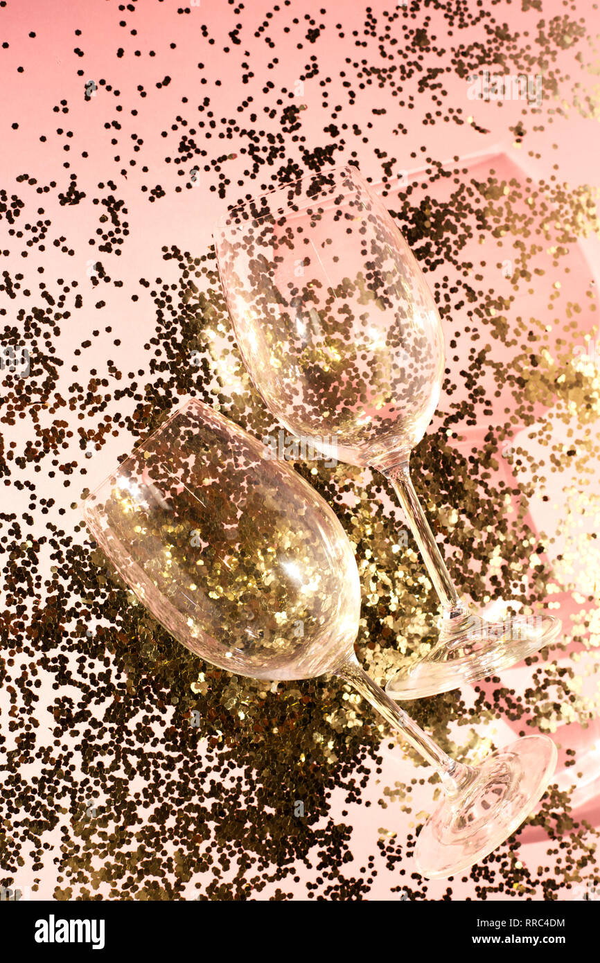 Gobelets en verre vide pour champagne en confettis d'or sur la table. Arrière-plan de fête. Concept parti Banque D'Images