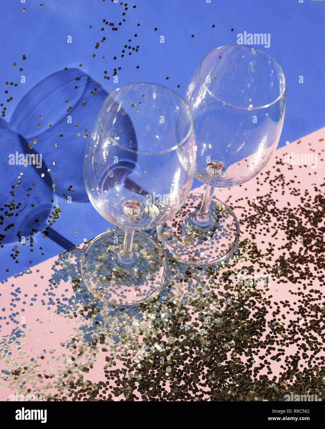 Gobelets en verre vide pour champagne en confettis d'or sur la table. Arrière-plan de fête. Concept parti Banque D'Images