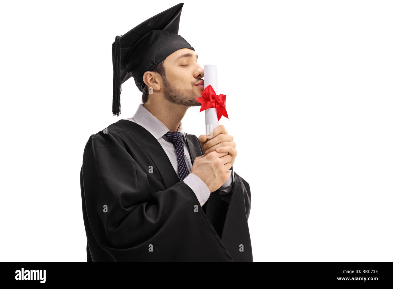 Jeune homme dans une graduation gown et capuchon, embrassant un baccalauréat Diplôme isolé sur fond blanc Banque D'Images