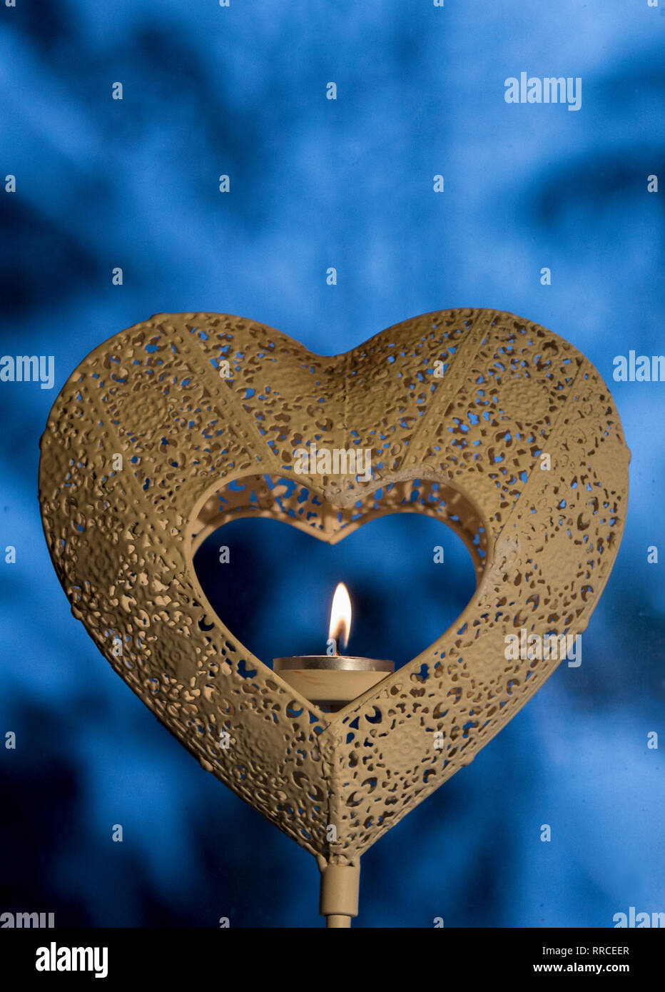 Au coeur coeur porte-bougie avec flamme de bougie dans le noyau sur fond bleu de l'hiver. Banque D'Images