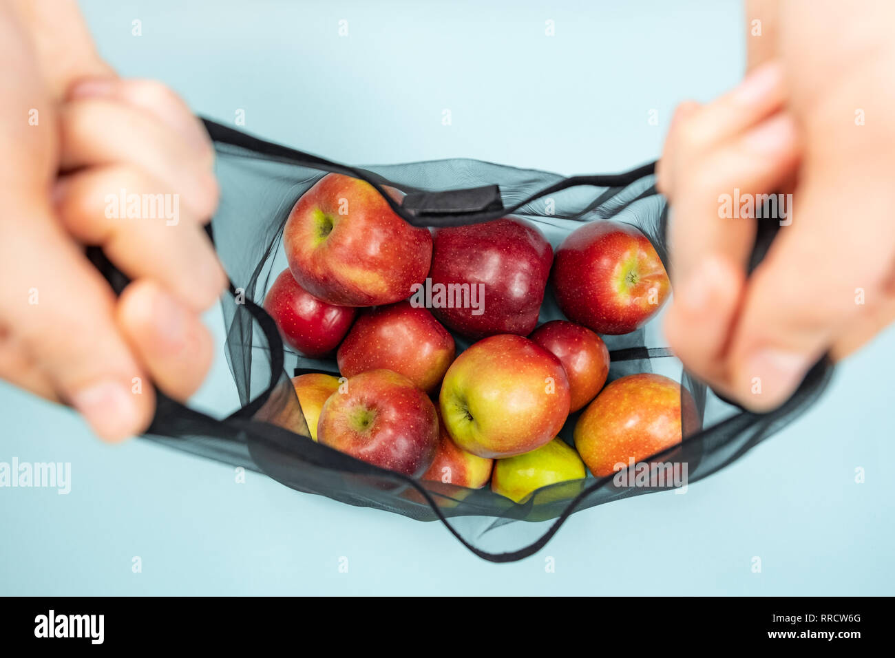 Tenant une chaîne réutilisable sac plein de pommes. Concept d'emballage écologique durable : faire les courses avec un sac multi-usage pour réduire l'empreinte écologique Banque D'Images