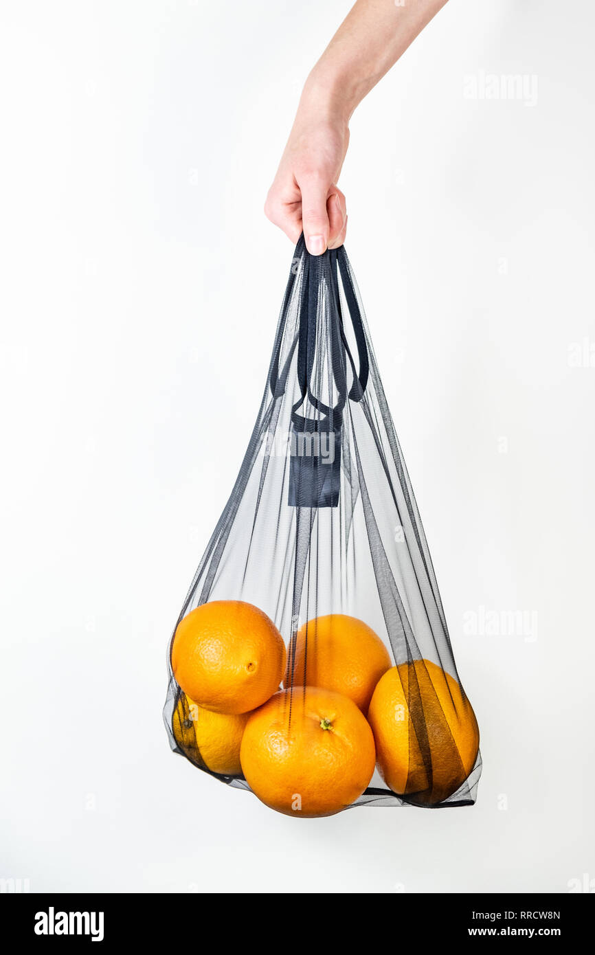 Tenant une chaîne réutilisable sac plein d'oranges. Concept d'emballage écologique durable : faire les courses avec un sac multi-usage écologique pour réduire foo Banque D'Images