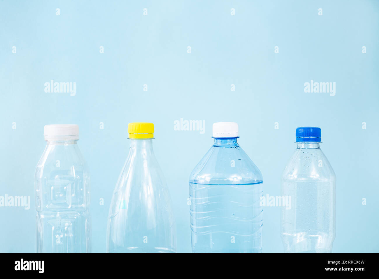 Les déchets plastiques concept : jetée diverses bouteilles d'eau dans le fond bleu, vue détaillée. Les bouteilles en plastique à usage unique en ligne permanent, représentant de l'image Banque D'Images