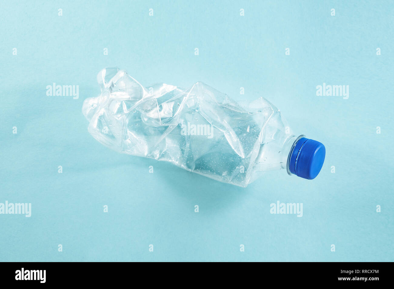 Les déchets plastiques concept : jetés dans la bouteille d'eau froissée, fond bleu vue détaillée. Un jeté de bouteilles en plastique à usage unique représentant une Banque D'Images