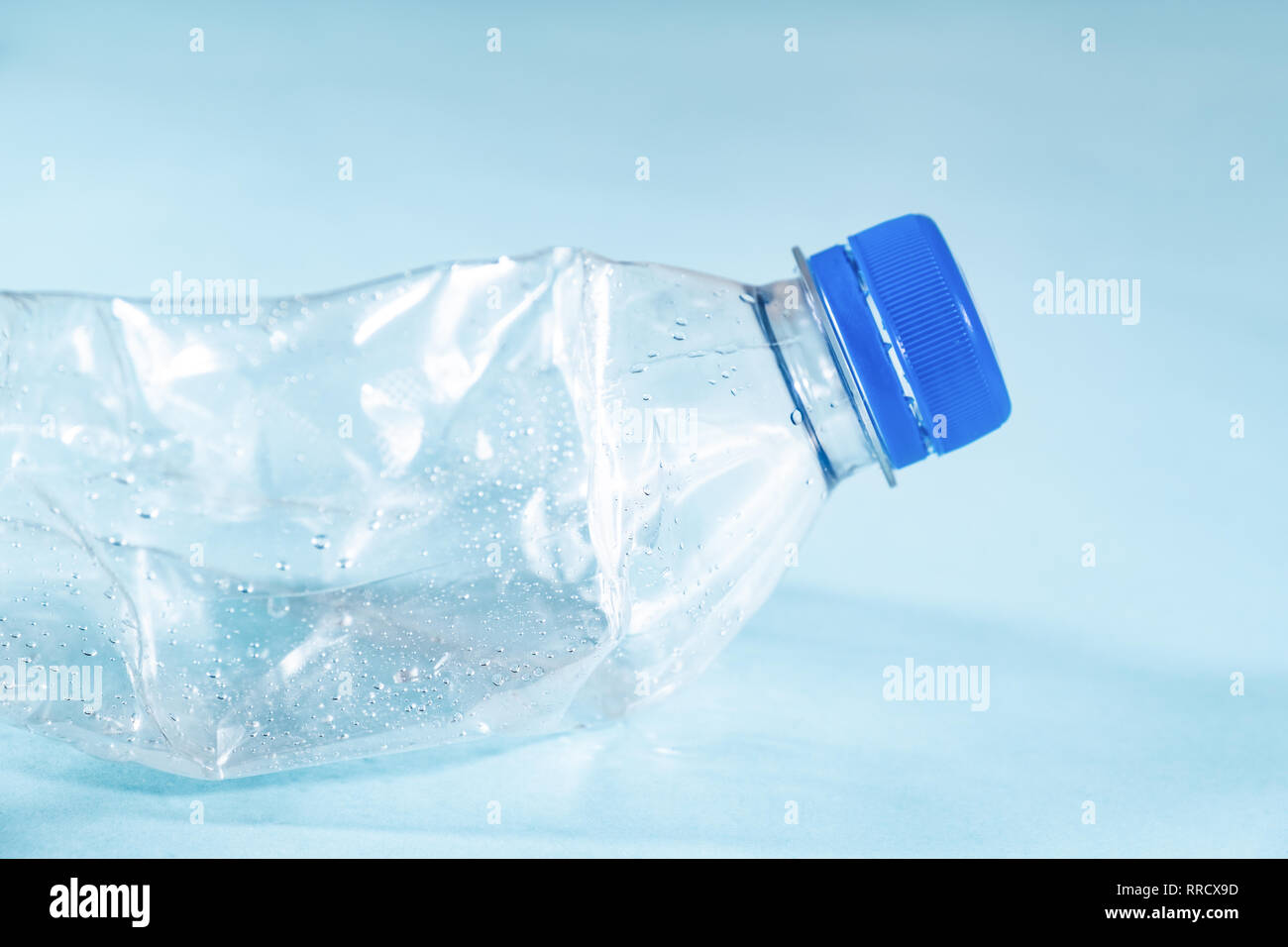 Les déchets plastiques concept : jetés dans la bouteille d'eau froissée, fond bleu vue détaillée. Vue rapprochée d'un jeté de bouteilles en plastique à usage unique dep Banque D'Images