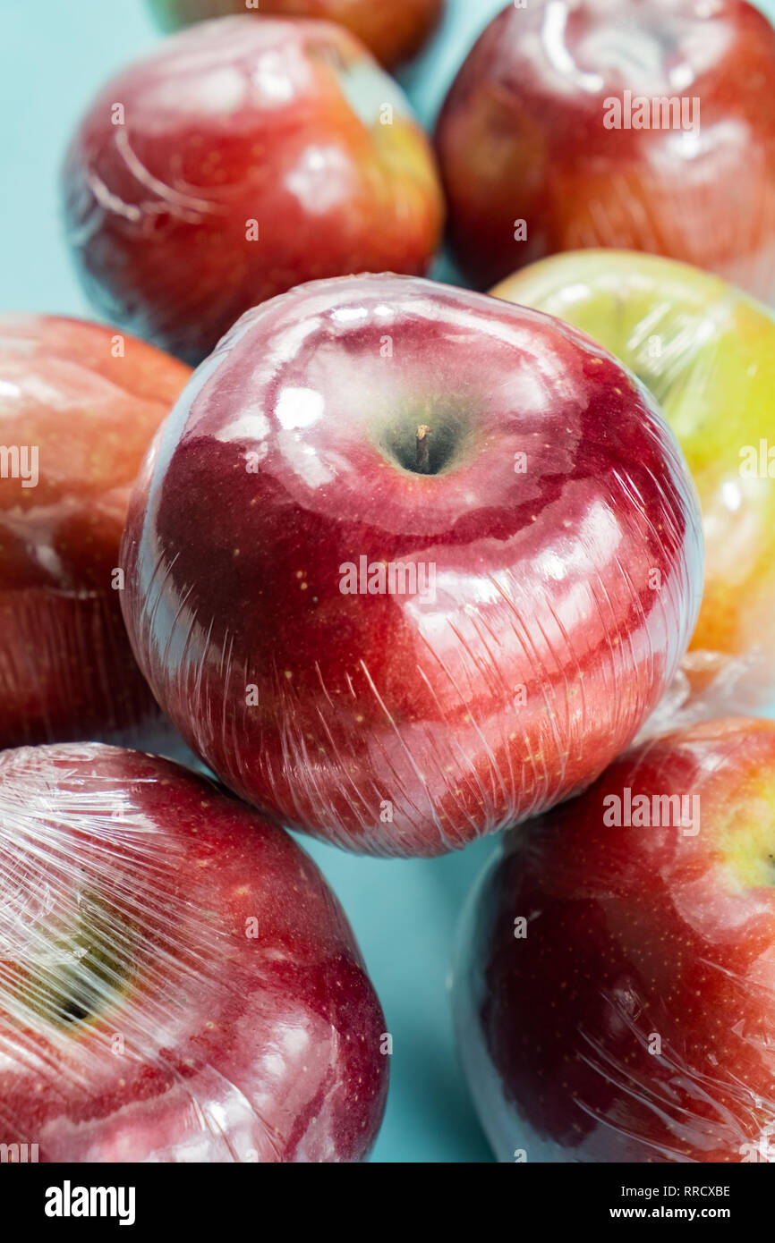 Concept d'utilisation de plastique excessive : pommes fraîches dans la cuisine d'enrubannage. Plus injustifié des produits alimentaires préemballés : fruits frais dans l'emballage plastique, close-up view Banque D'Images