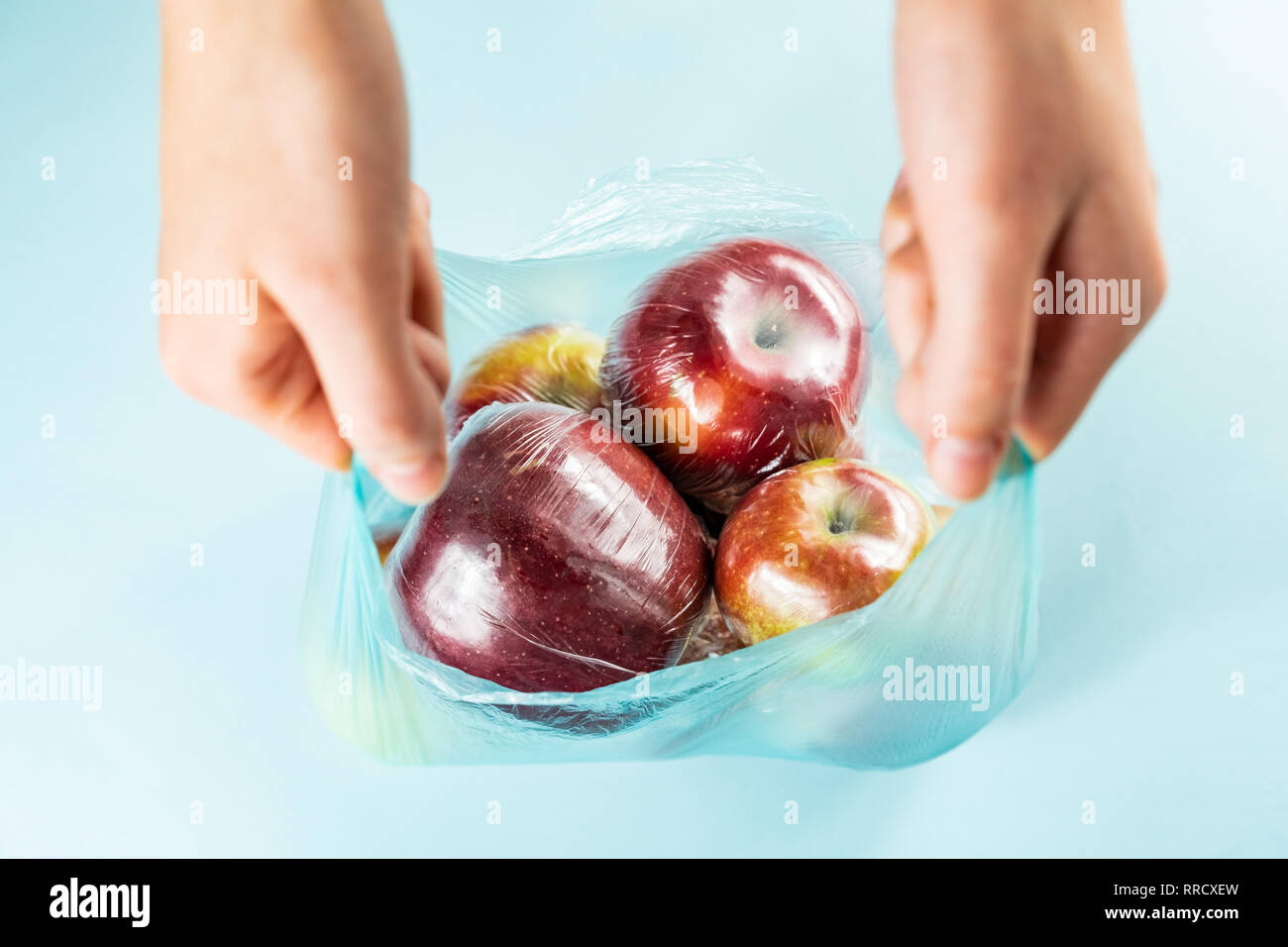 Concept d'utilisation de plastique excessive : pommes fraîches dans la cuisine l'envelopper dans un sac en plastique. Plus injustifié des produits alimentaires préemballés, vue d'en haut Banque D'Images