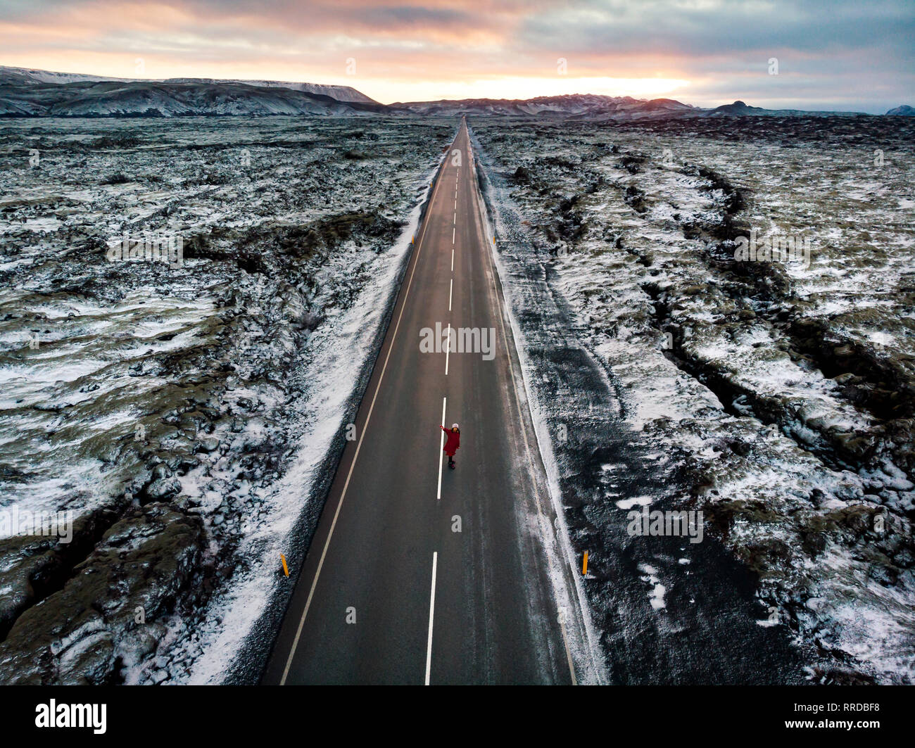 Female traveler sur route islandaise entourée de plaines de lave couvertes de neige Banque D'Images