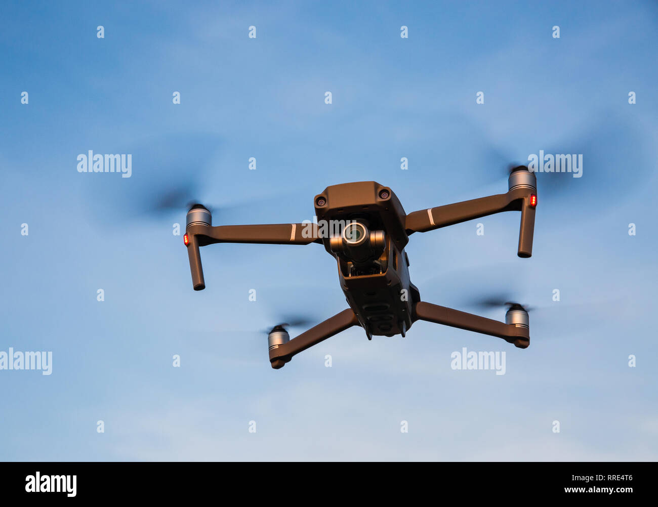 Un low angle view of a futuristic drone quadcopter en vol avec quatre  hélices tournant et drone planant sur un fond de ciel bleu Photo Stock -  Alamy