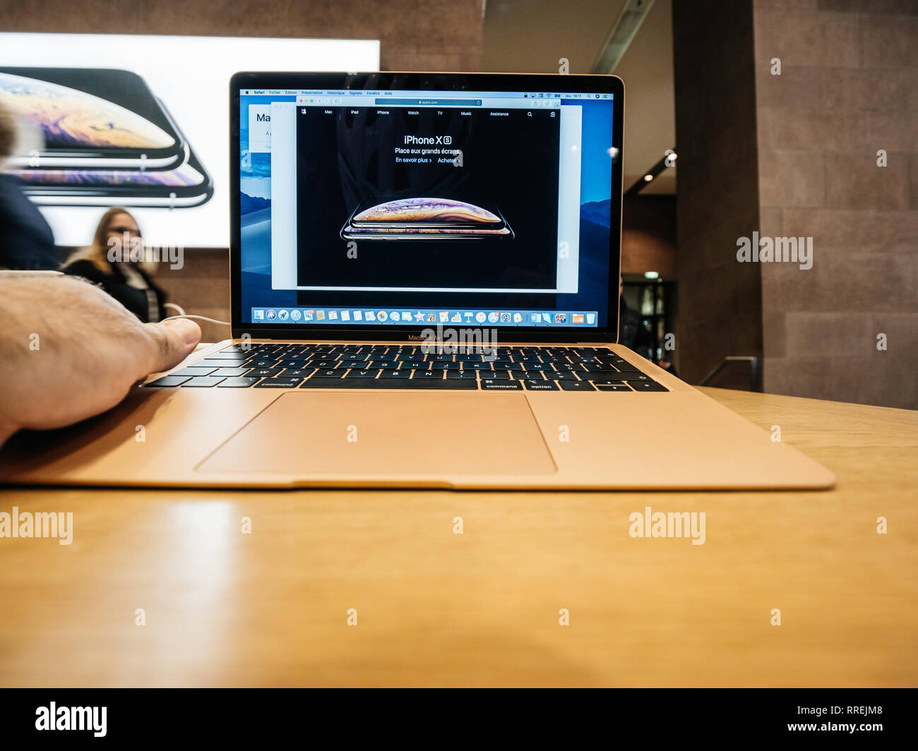 PARIS, FRANCE - Nov 8, 2018 : man main touchant le nouveau Apple MacBook Air ordinateur portable léger avec écran Retina et nouveau CPU - La lecture sur iPhone XS Banque D'Images