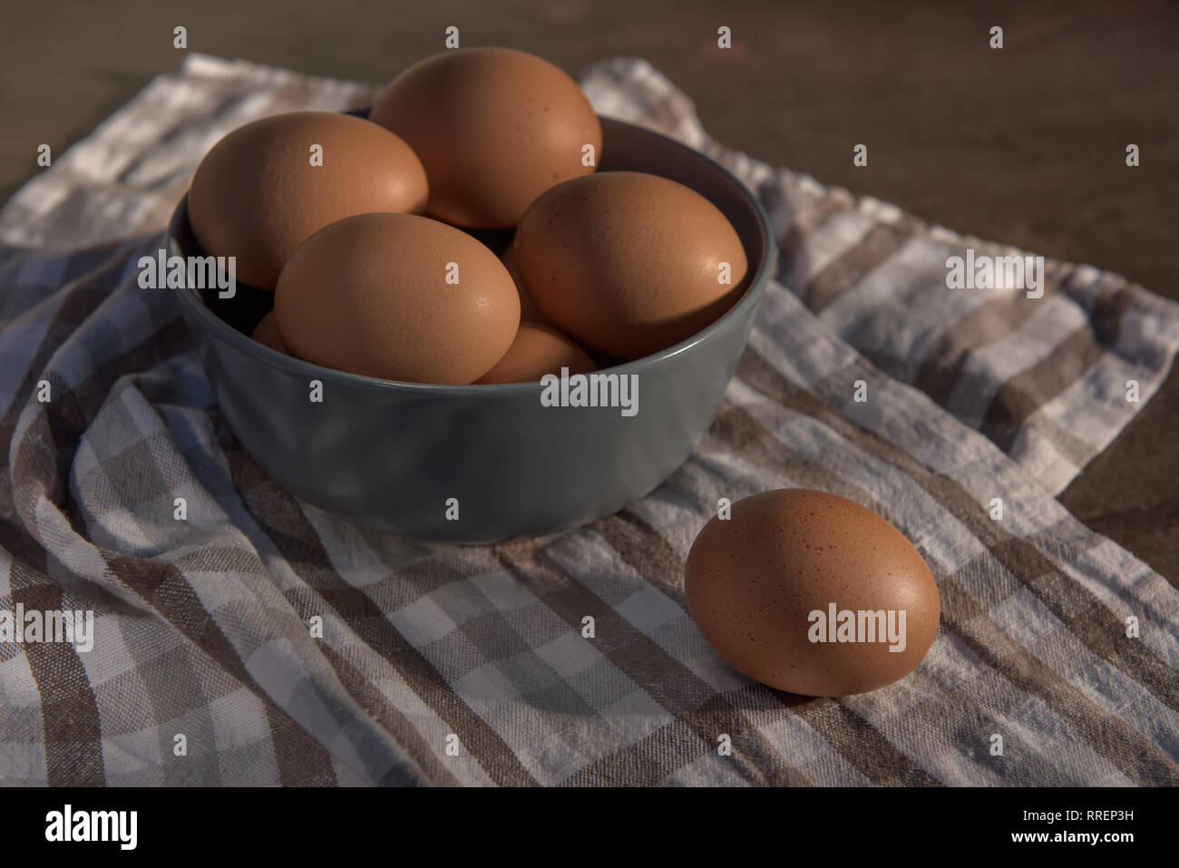 Les oeufs de poule dans un bol gris sur une serviette à carreaux. Banque D'Images