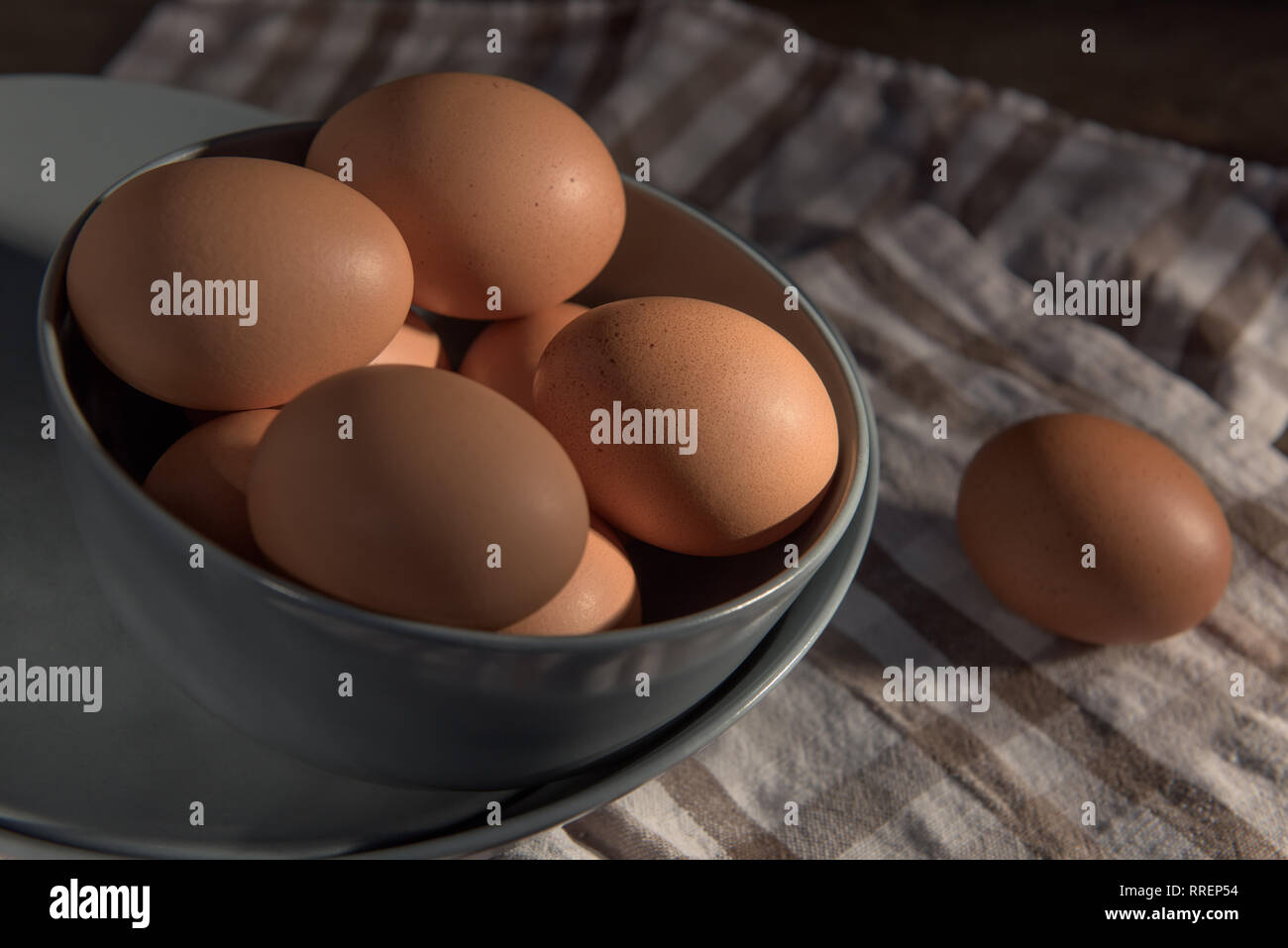 Les oeufs de poule dans un bol gris sur une serviette à carreaux. Banque D'Images