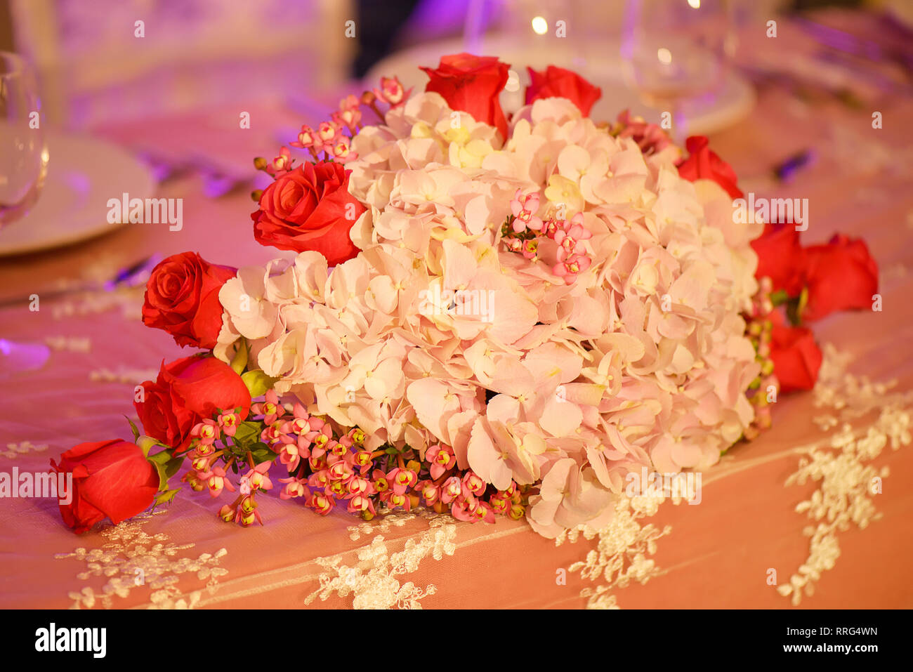 Arrangement floral élégant dans un ovale avec bouquet pastel pink hortensias et roses rouges, placés sur une table, comme une pièce maîtresse à un mariage Banque D'Images