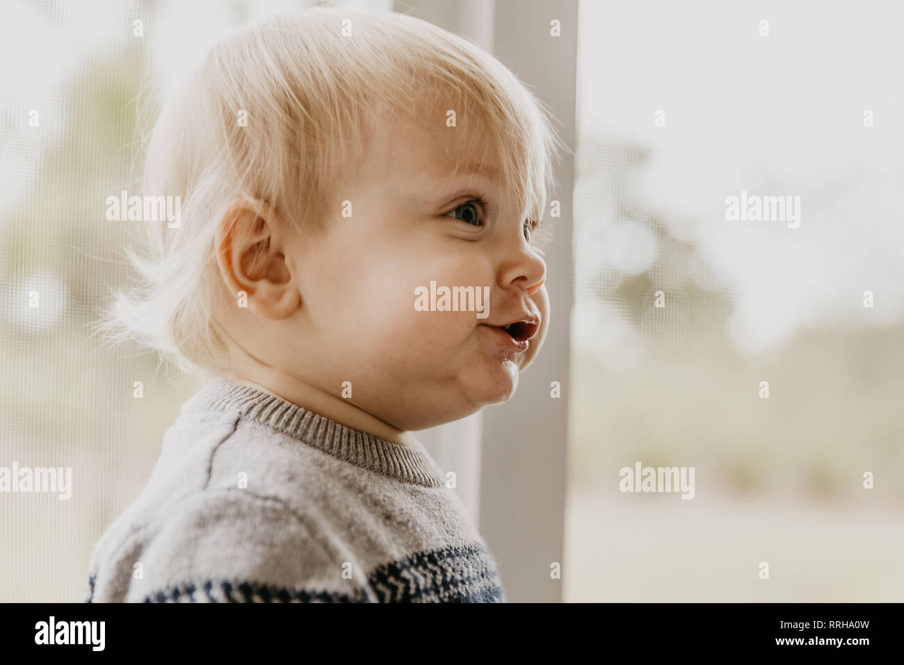 Cute Adorable petite blonde tout-petit enfant rire, s'amuser, et faire face à l'extérieur à la maison stupide sur le Patio porche blindé Banque D'Images