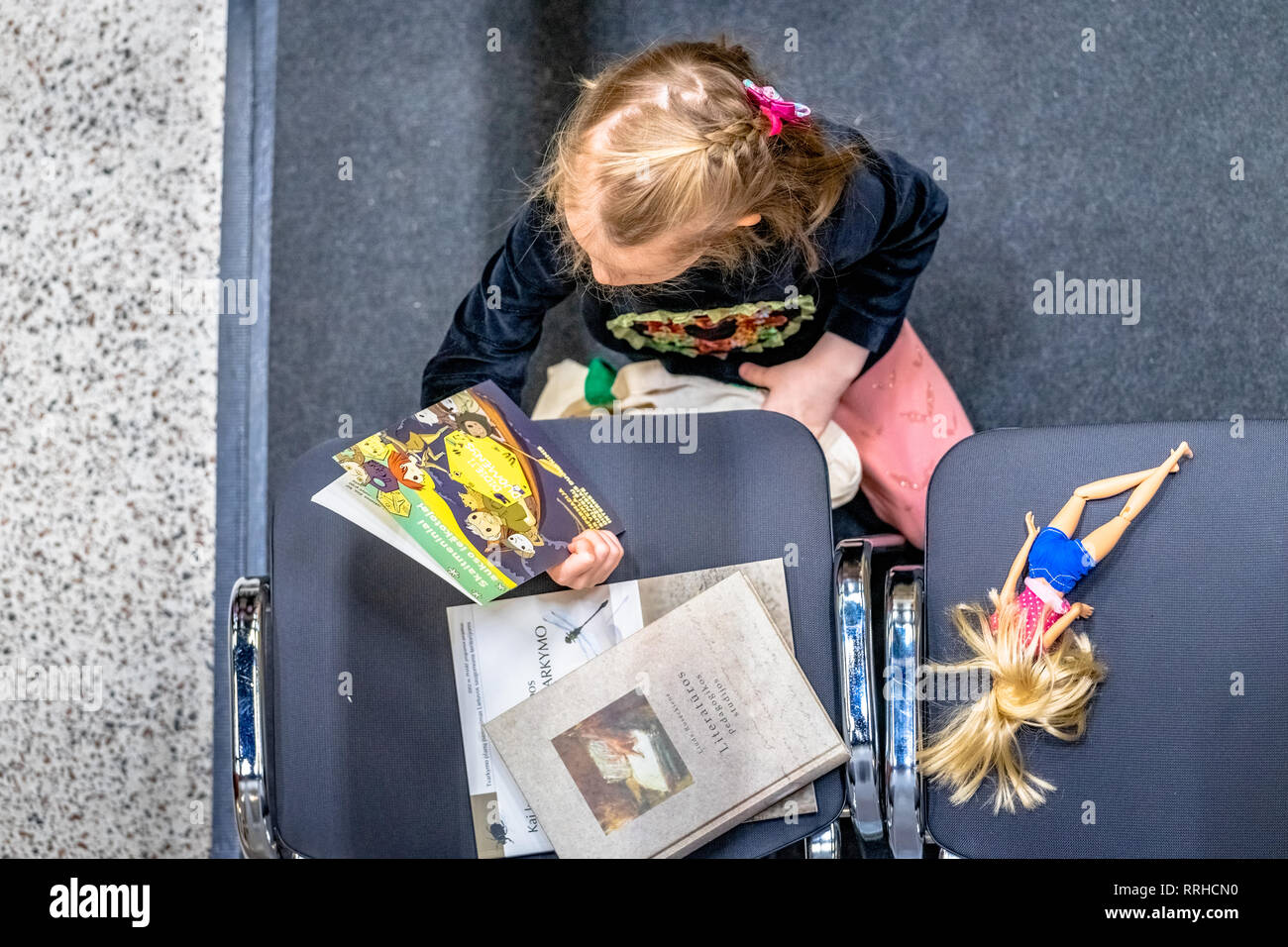 Le livre de Vilnius. Petite fille est en train de lire un livre sur big data. À côté d'elle se trouve sa poupée sur une chaise Banque D'Images