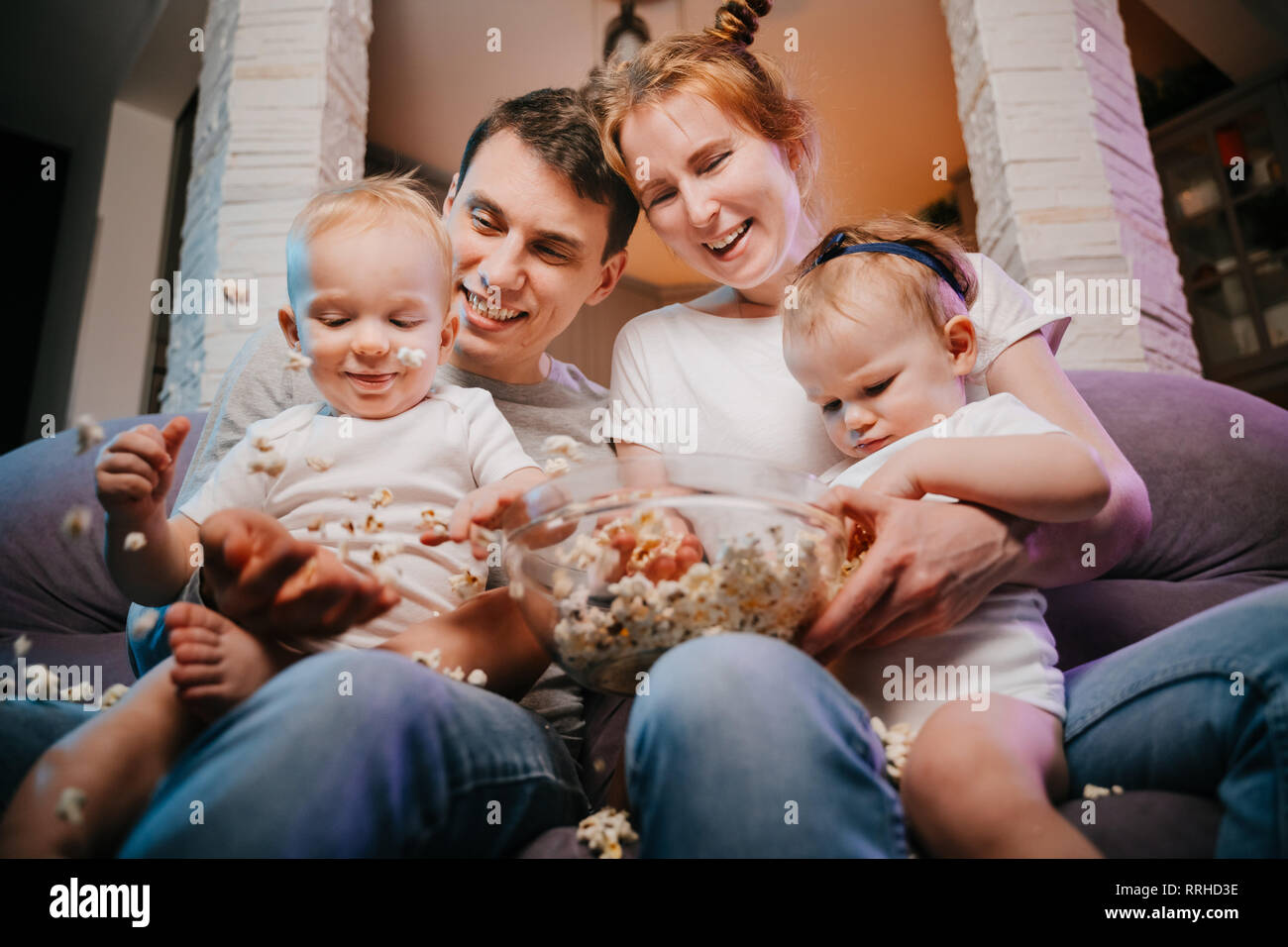 Jeune famille avec enfants eating popcorn sur le canapé. Banque D'Images