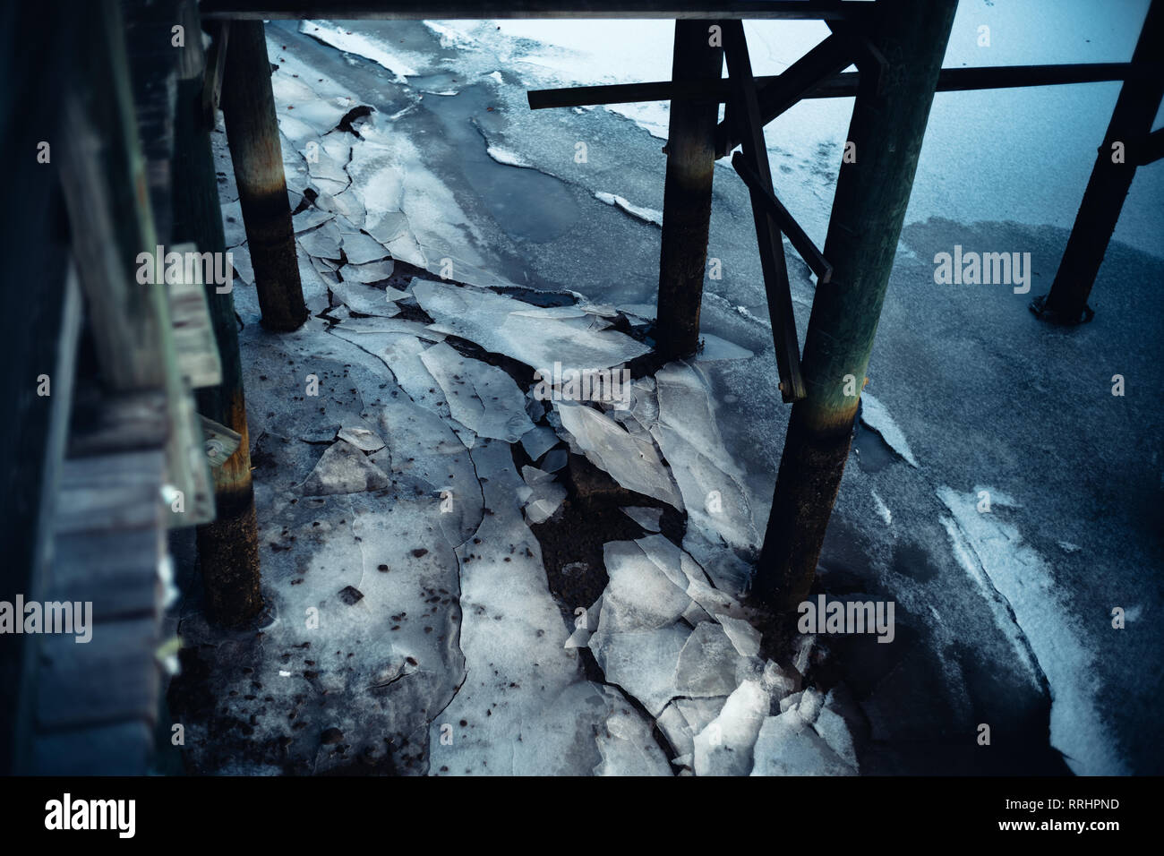 L'eau gelée et de glace glacial se fissure sous la pression le long d'une rive marina ligne à côté d'un quai. Banque D'Images