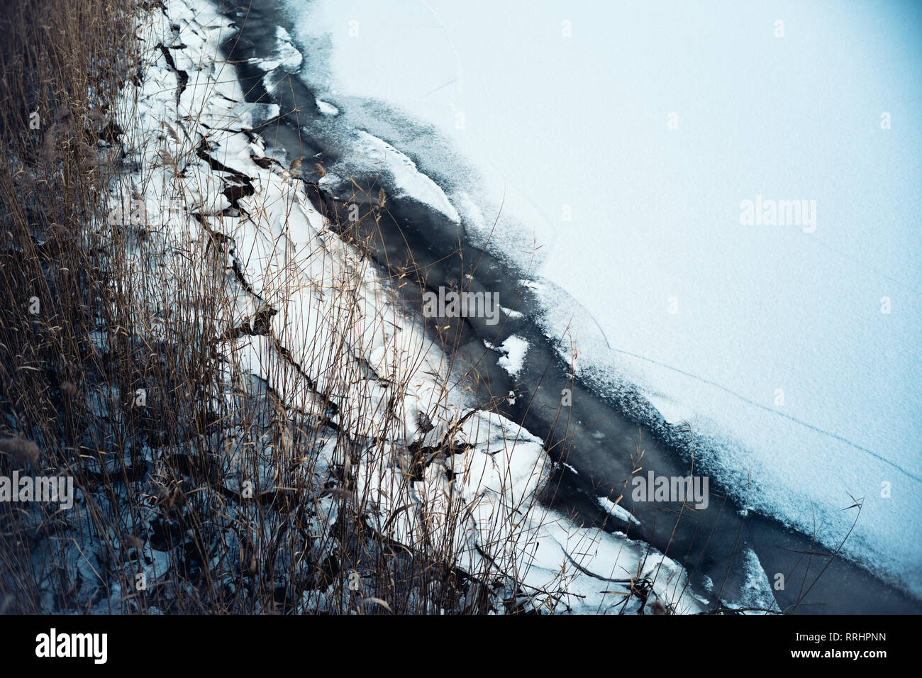 L'eau gelée et de glace glacial se fissure sous la pression le long d'une rive marina ligne à côté d'un quai. Banque D'Images