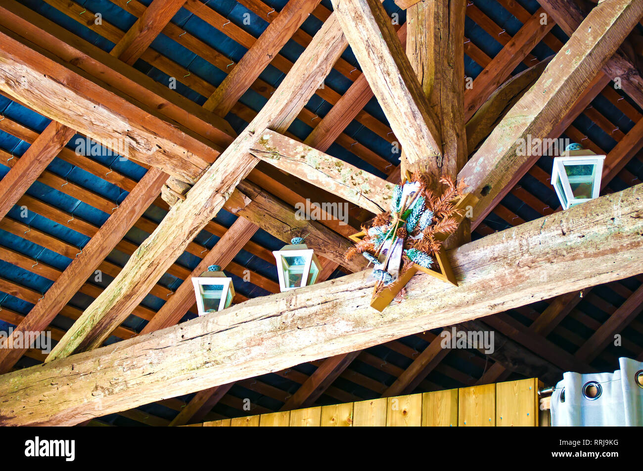 De nombreuses poutres en bois orange formant le plafond d'une maison d'habitation. Décorations faites de branches de pins et les cônes. Plusieurs lanternes Banque D'Images